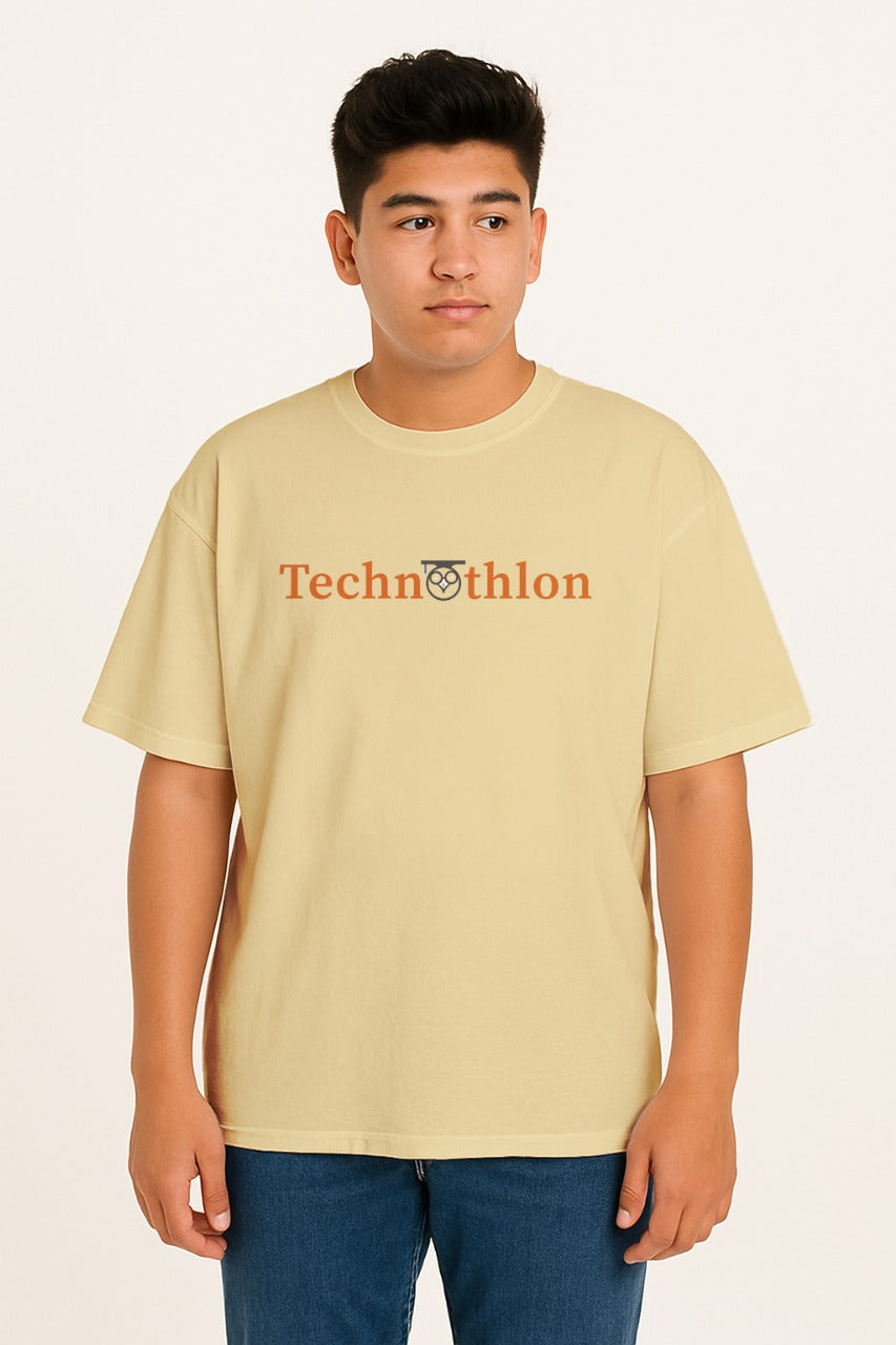 Person wearing a beige t-shirt with 'Technothlon' logo on a plain background. technothlon iit guwahati. iit guwahati technothlon